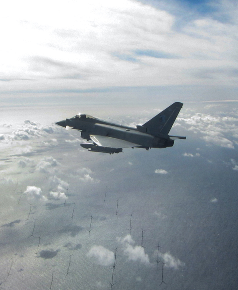 fighter jet over wind farm